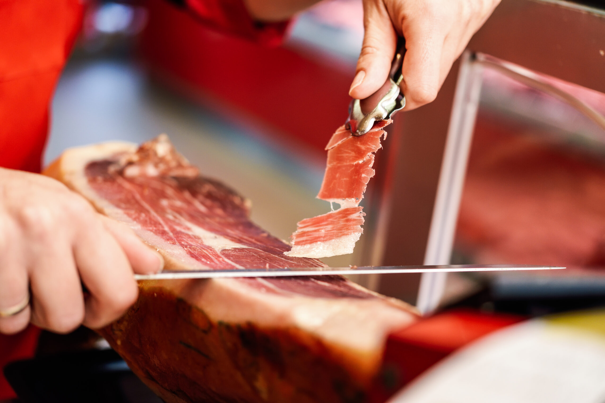 Professional cutter carving slices from a whole bone-in serrano